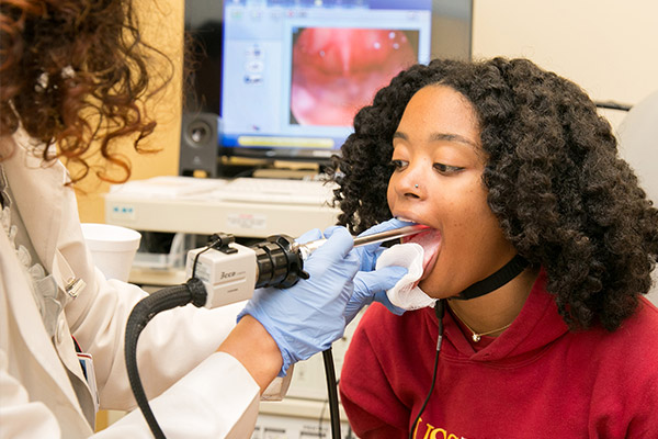 Doctor examines a female patient's vocal cords with an endoscope.