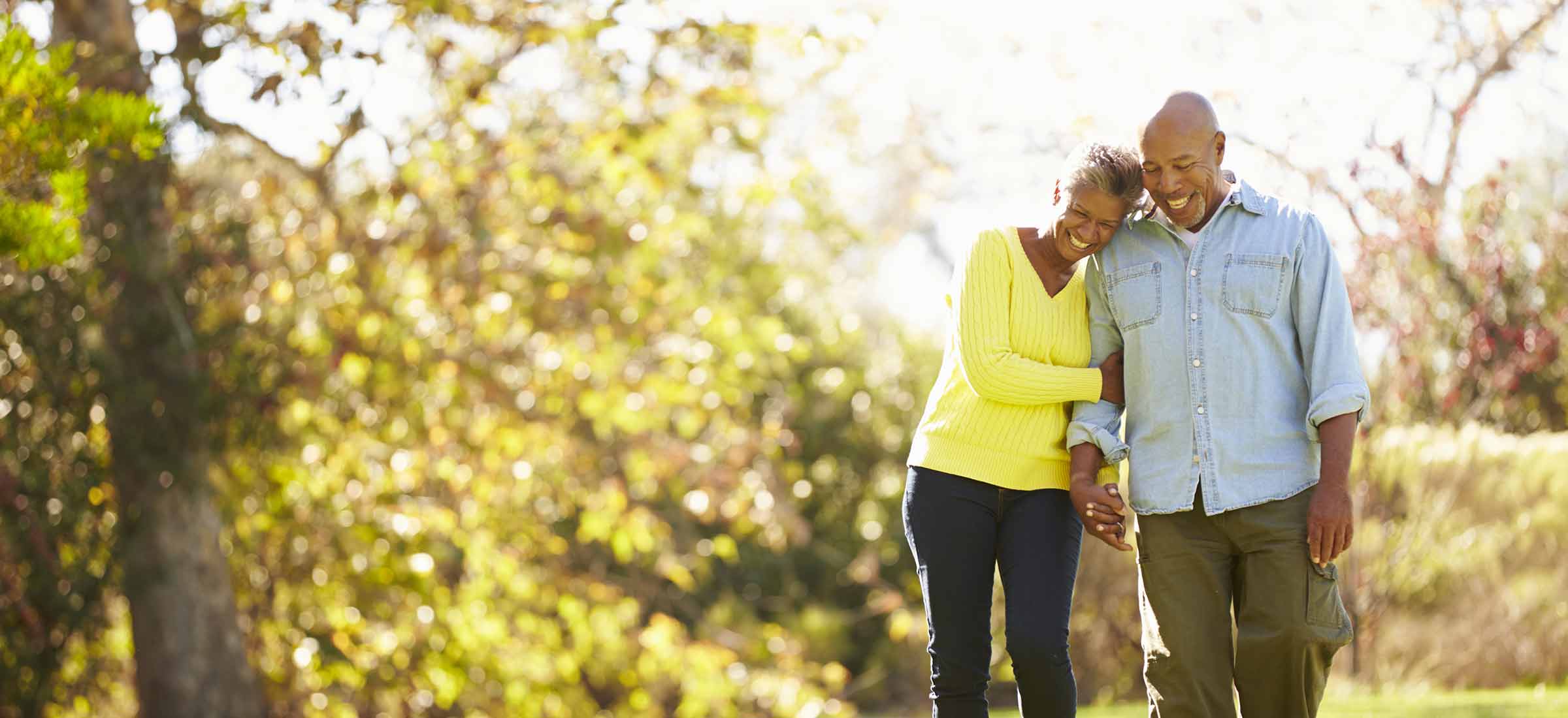 Senior couple walking through autumn woodland.