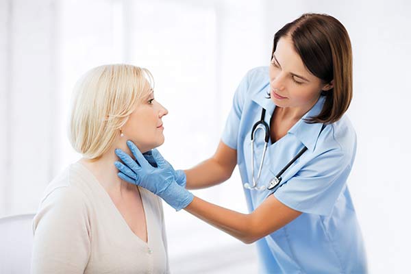 A doctor touches a woman's neck.