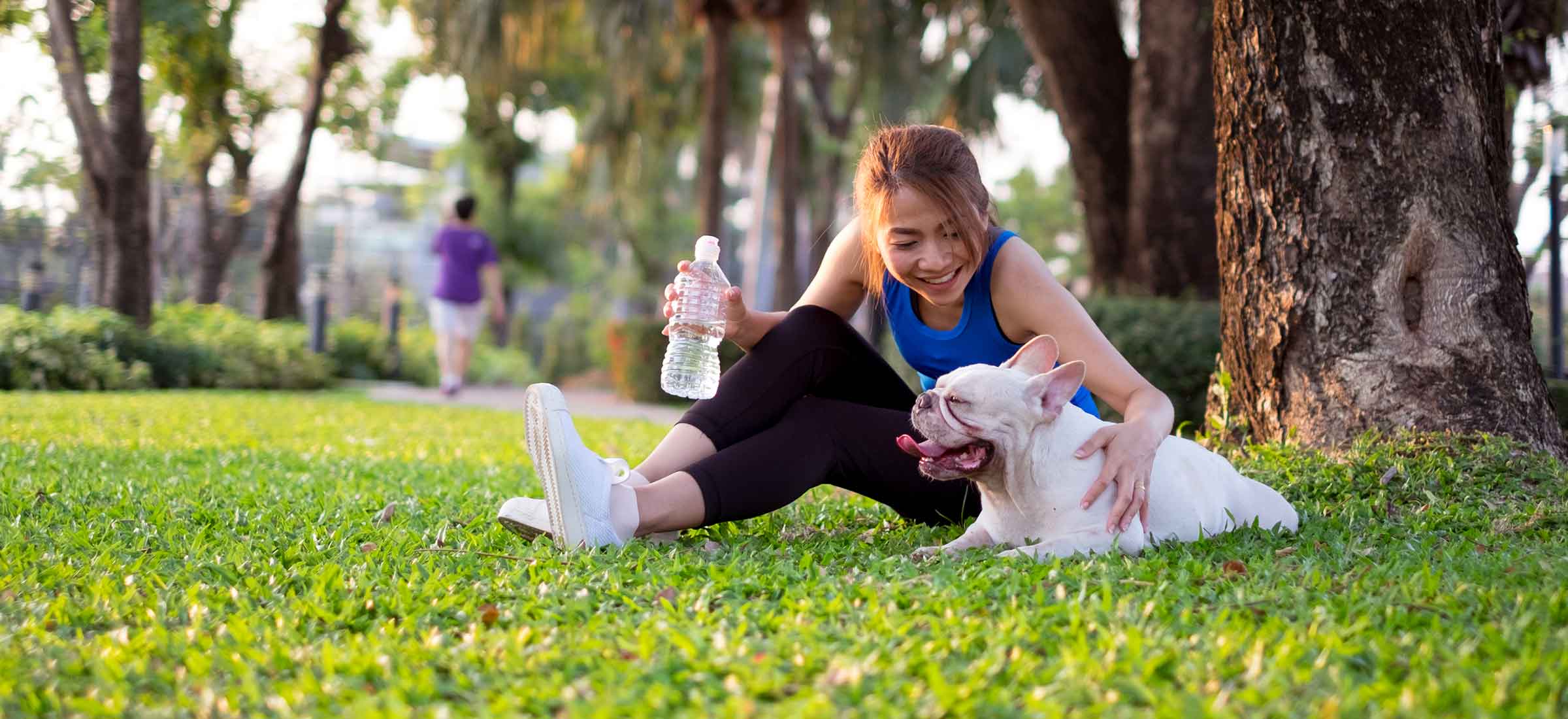 Asian woman sitting and playing with her dog after jogging in the morning.