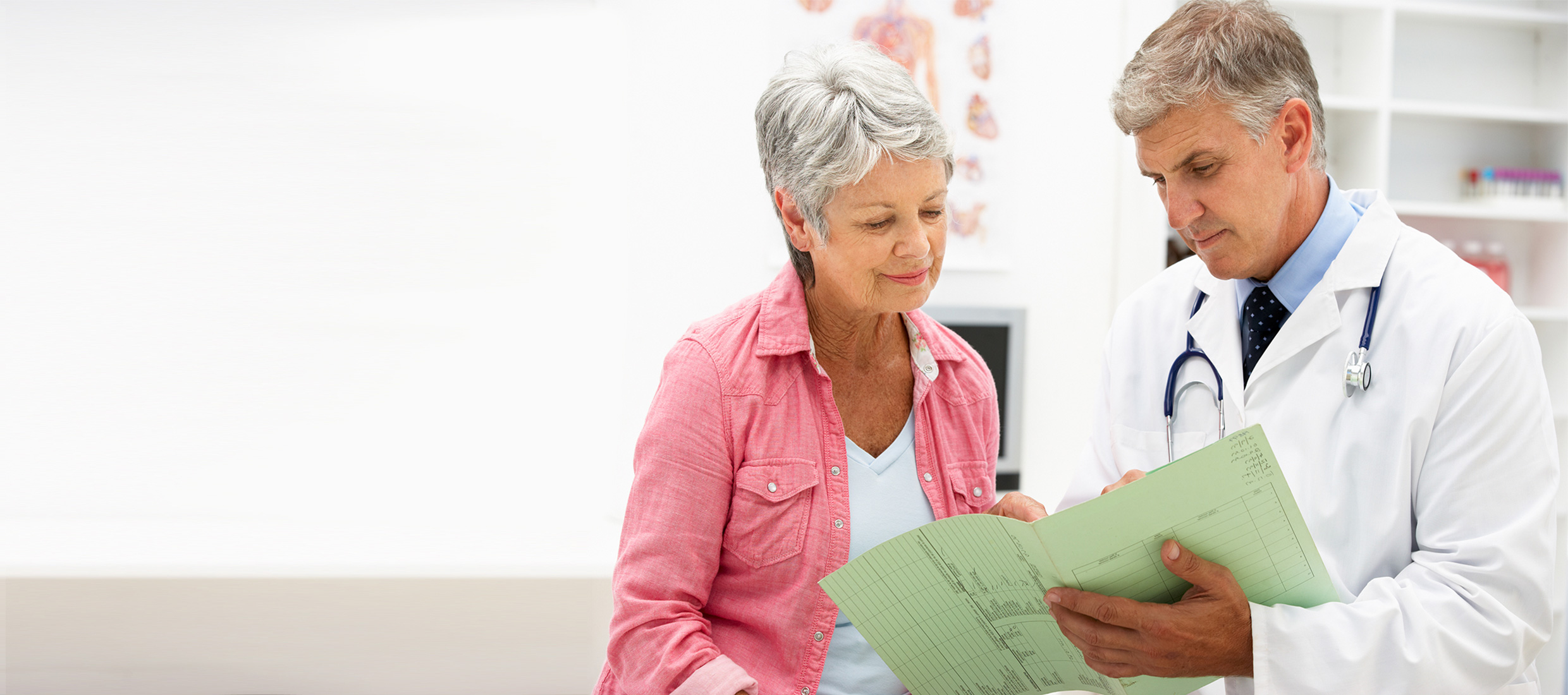 Female patient looks at a medical document held by a male doctor in an examining room