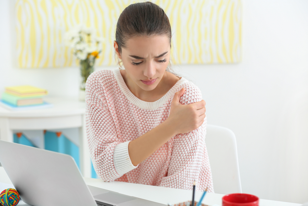 A woman experiences should pain while working on a computer