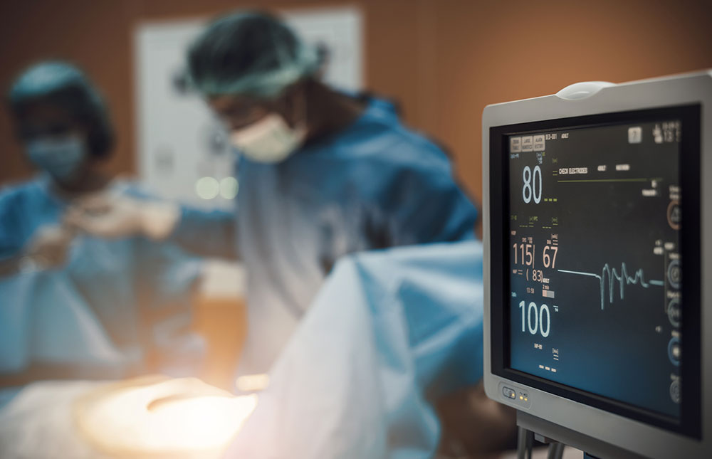 Close up of a monitor in a room with surgeons in the background.