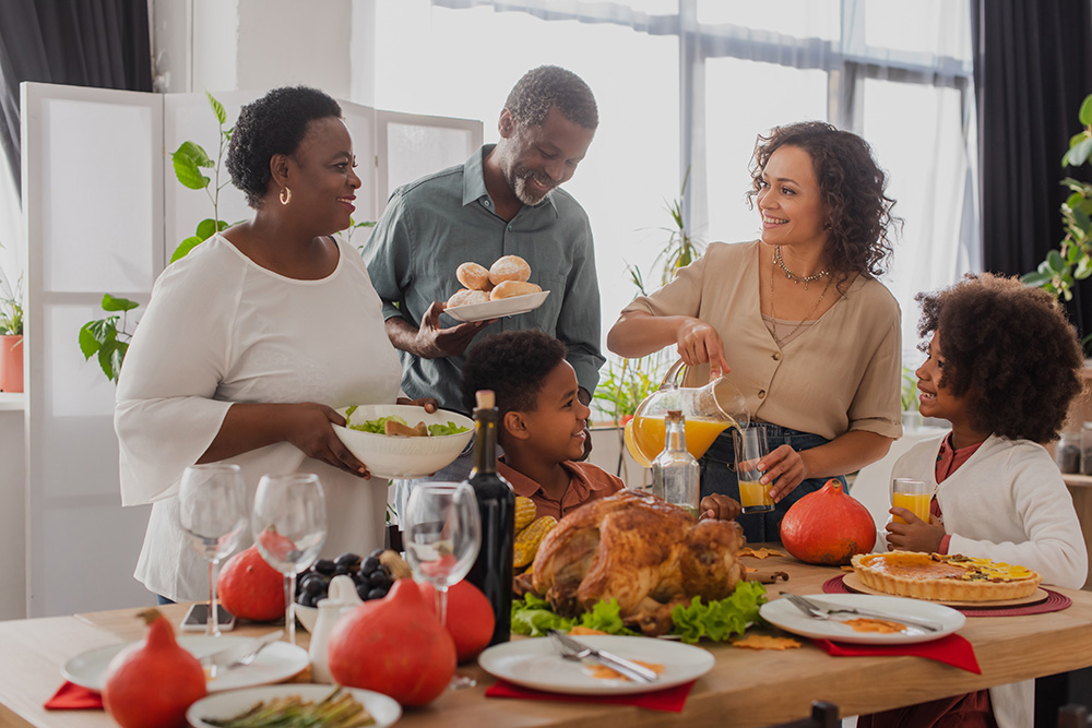 A family sits around a dinner table eating healthy food during the holidays.