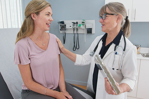 Doctor counsels young adult female patient in clinic.